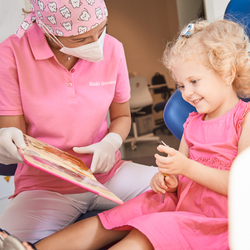 Studio Grendene - dottoressa mostra a paziente bambina un libro su come lavarsi bene i denti